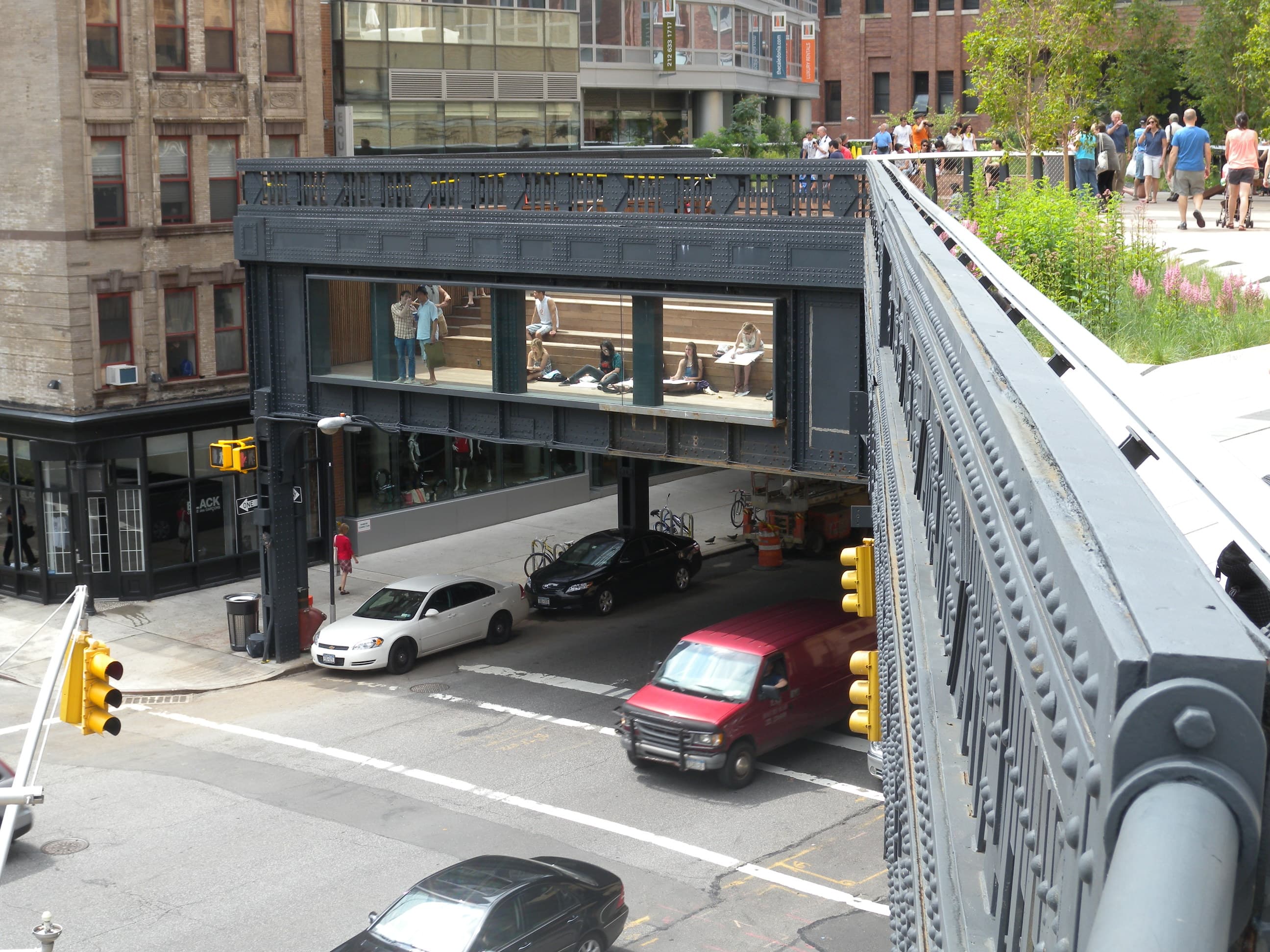 The High Line park after opening — wood-plank pathway threaded through perennial plantings, glass railings, and seating.
